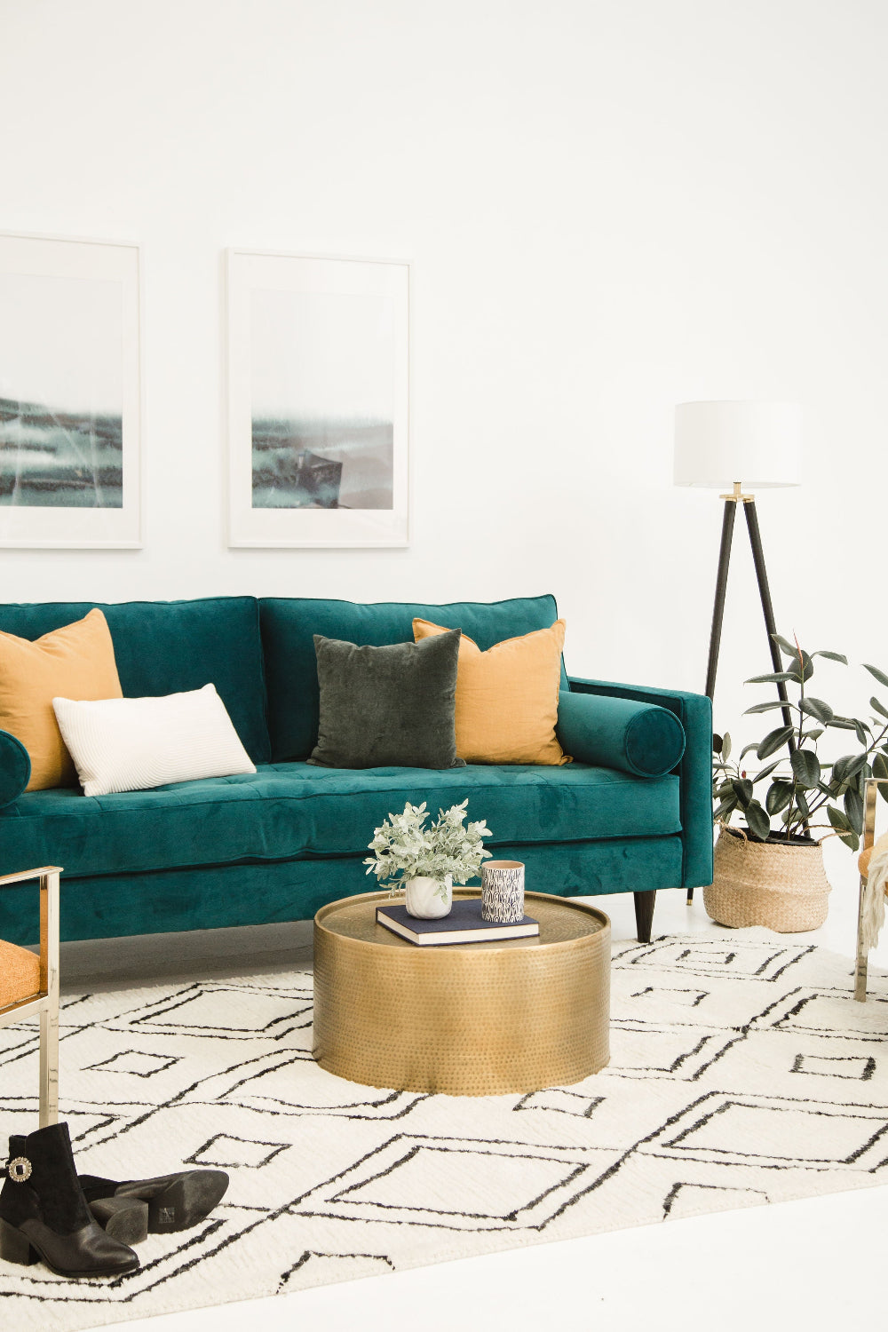 Living room with teal sofa, gold coffee table, and decorative elements.
